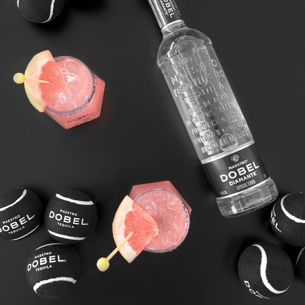 Dobel tennis balls with cocktail and bottle of Dobel Diamante Cristalino.