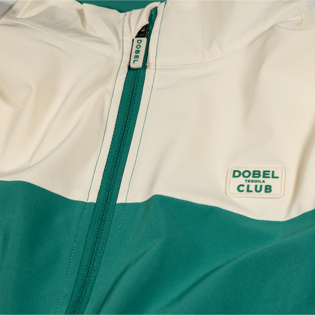 Detail shot of the front of the two-tone cream and green full zip jacket, featuring green zipper.