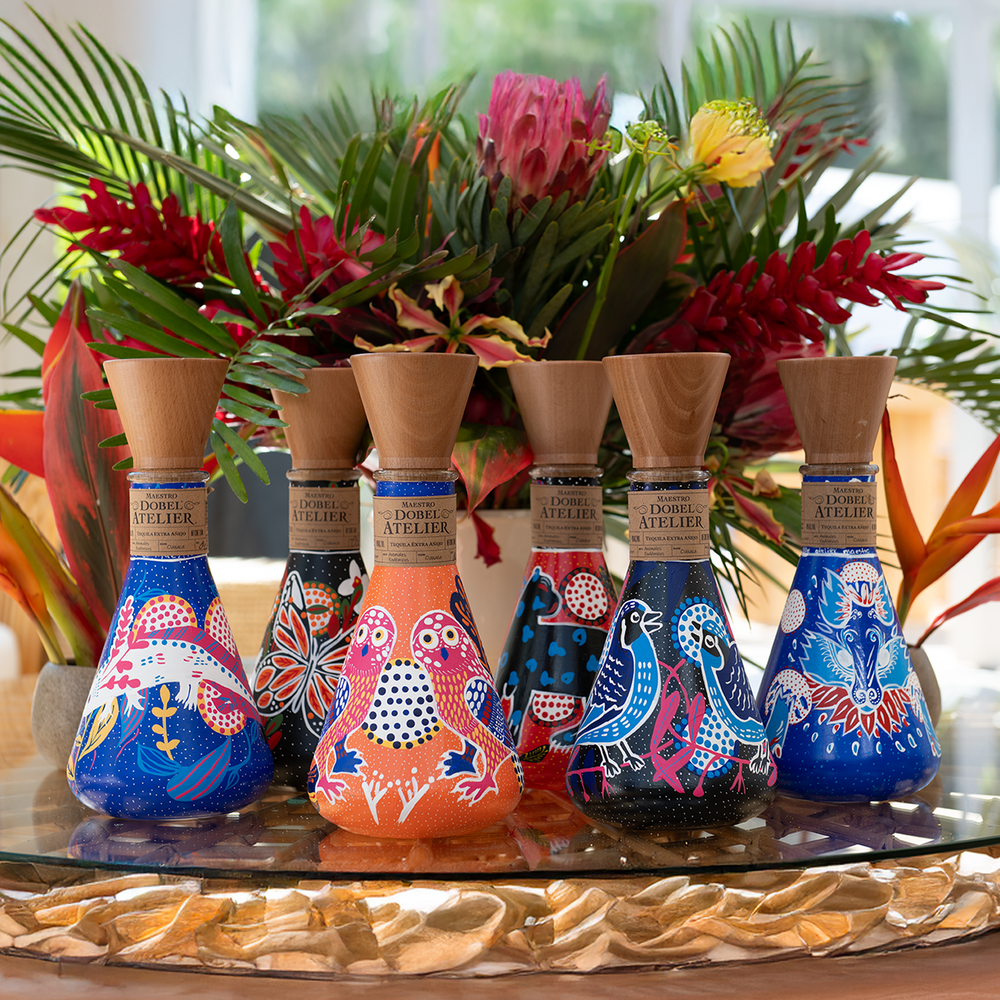 Dobel Atelier: Animales Endémicos Edition six bottles with colorful designs on a wooden surface.