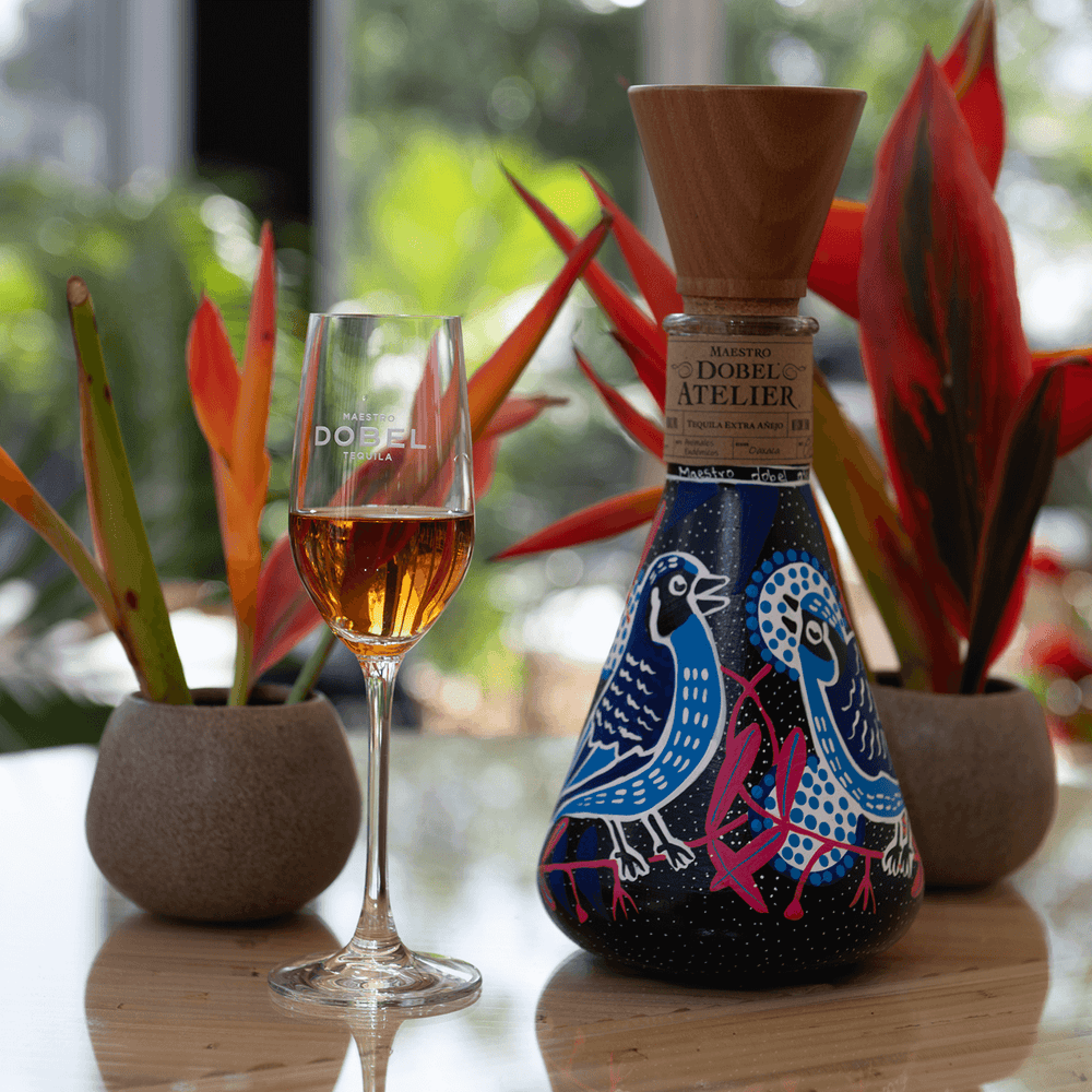 Dobel Atelier: Animales Endémicos Edition blue bottle with tequila flute on table.