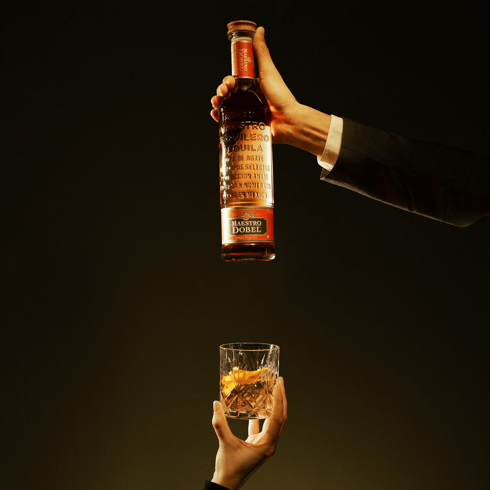 Dobel Añejo in hand with served drink.