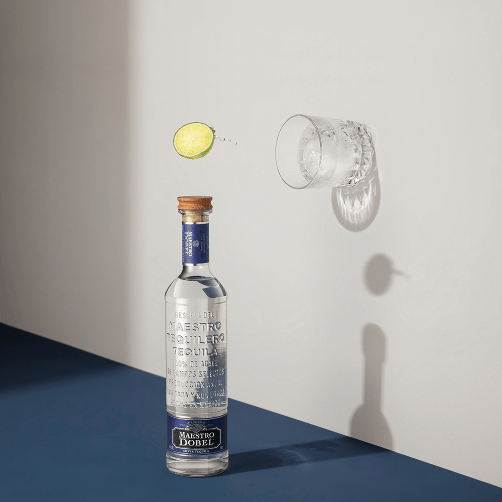 Dobel Blanco bottle with mixed cocktail and garnish bouncing off the wall.