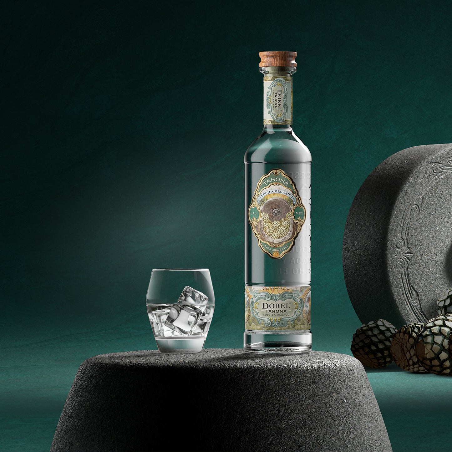 Dobel Tahona bottle on a stone next to a rocks serving of Tahona. 