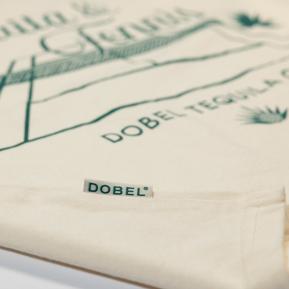 Close up detail shot of cream mid-crop shirt with large "Tequila & Tennis" graphic.