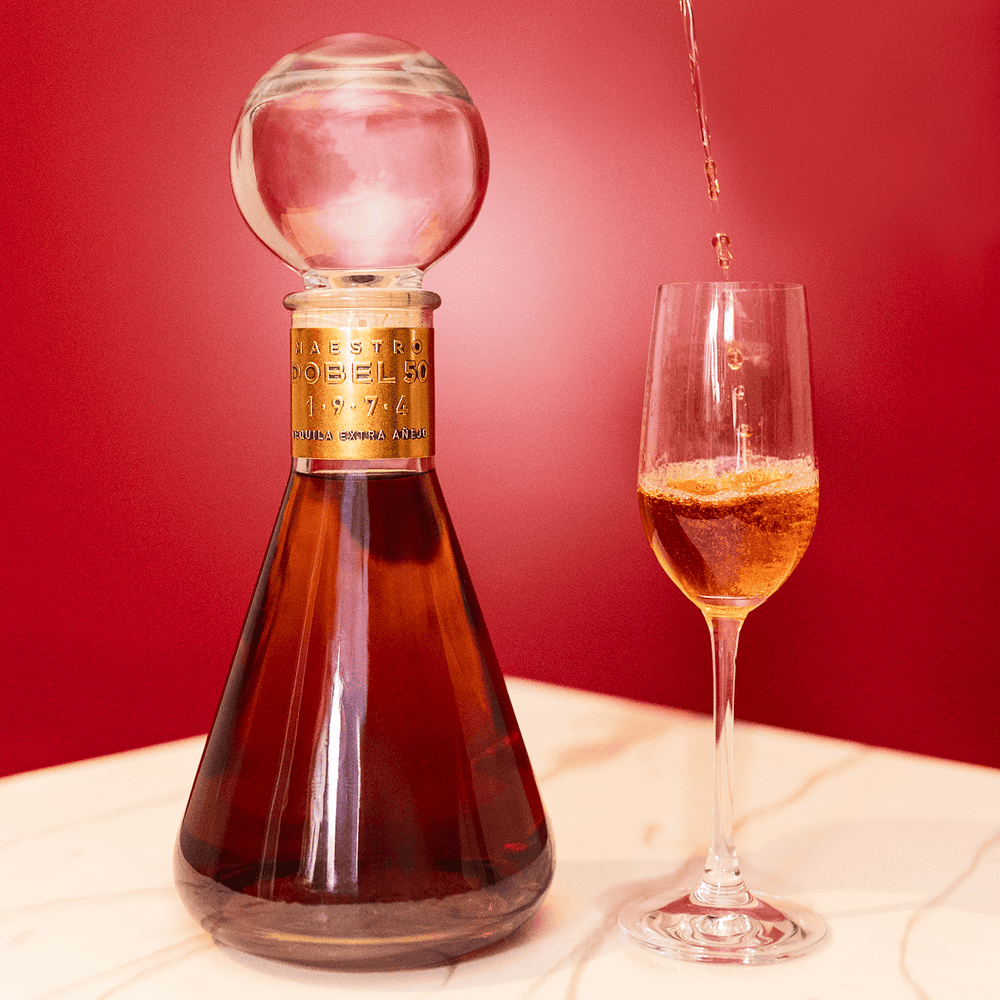 Dobel 50 Extra Añejo 1974 bottle with stemmed glass and liquid inside.
