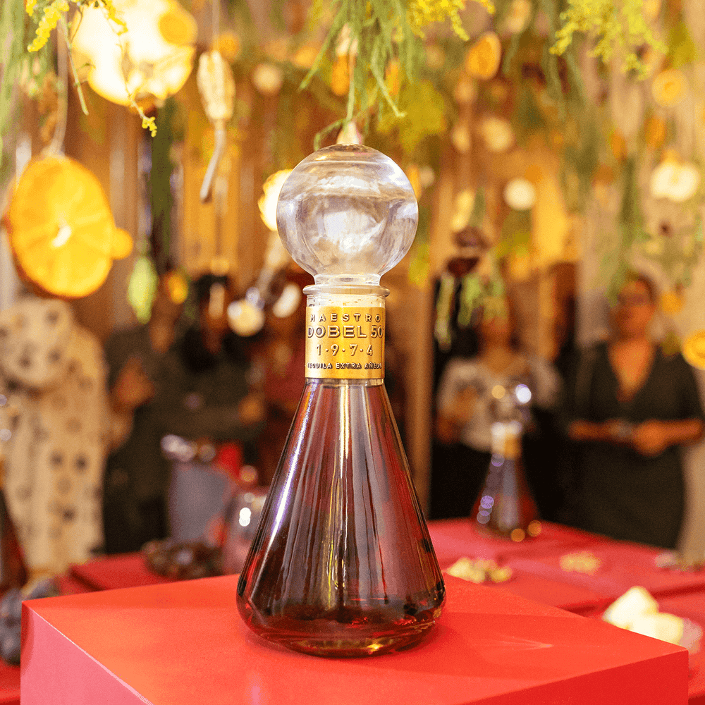 Dobel 50 Extra Añejo 1974 bottle with floral background at an event.